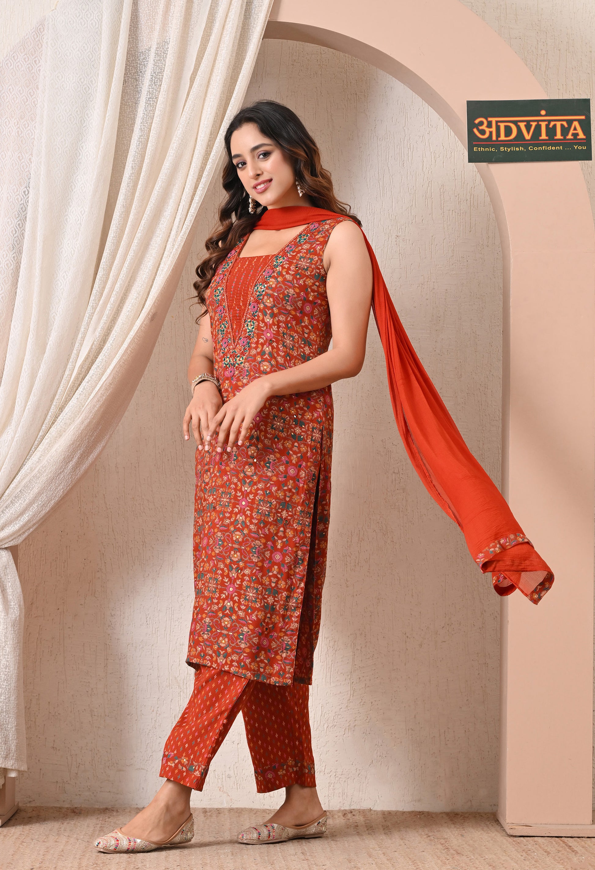Side pose of women rust orange ethnic kurta pant dupatta set