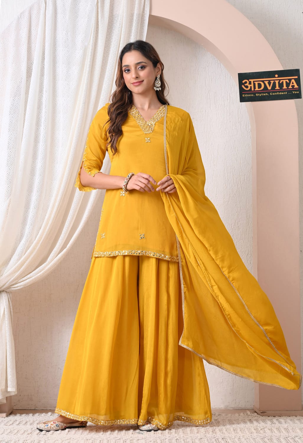 Woman wearing mustard yellow sharara suit with dupatta